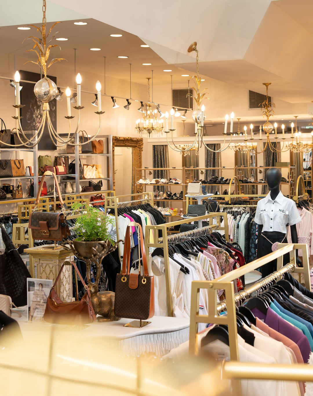 Interior of a clothing store with racks of clothes and handbags.